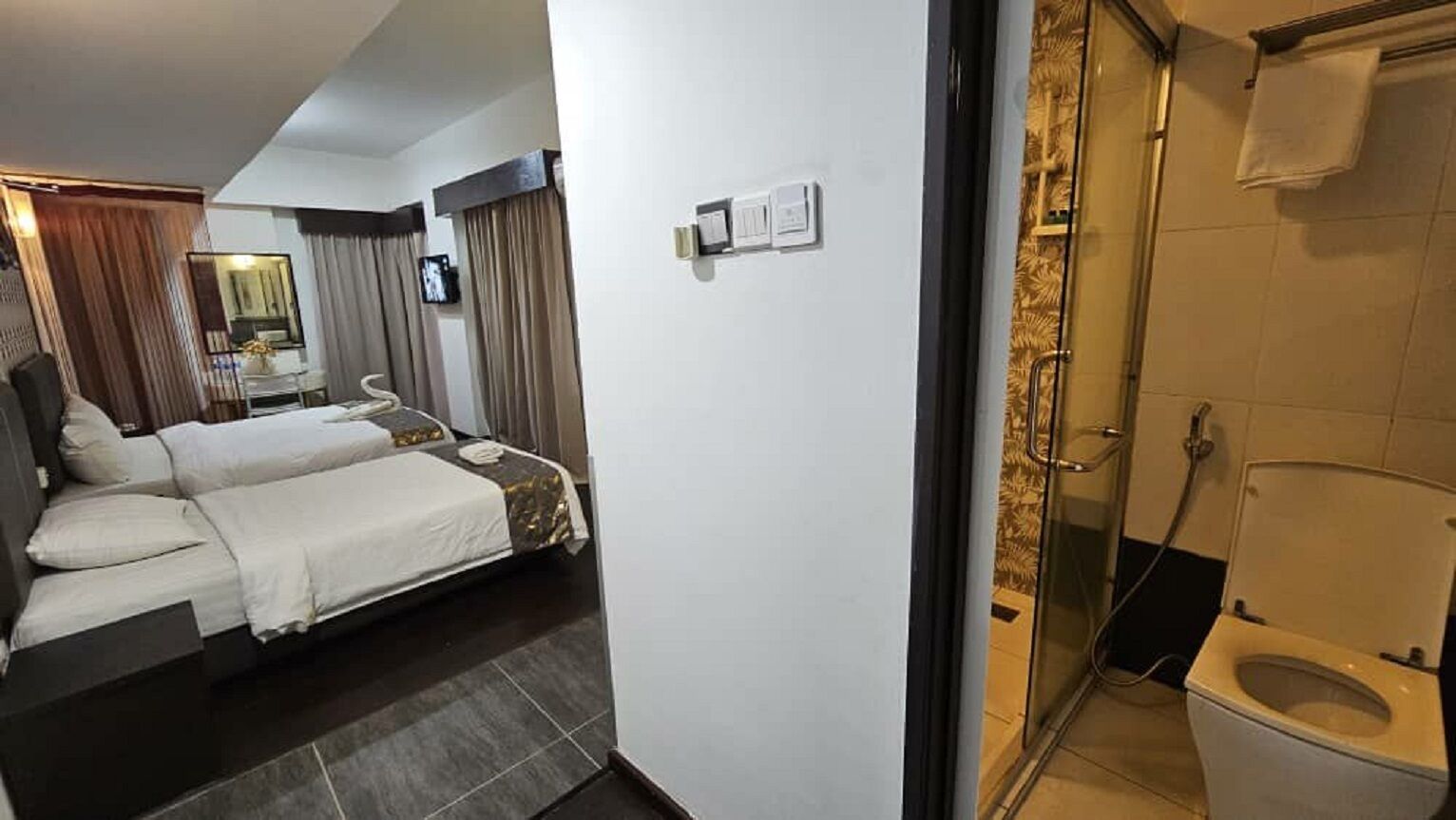 Habitación de hotel con cama, una mesita pequeña y zona de ducha.