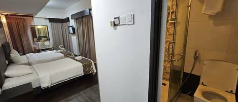 A hotel room with a bed, a small table, and a shower area.