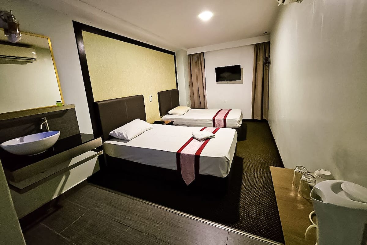 Une chambre d’hôtel avec deux lits, un lavabo, un miroir et un téléviseur à écran plat.
