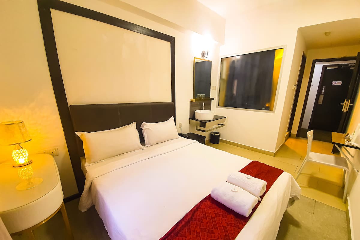 Une chambre d’hôtel avec un grand lit, des tables de chevet, un miroir et une fenêtre.