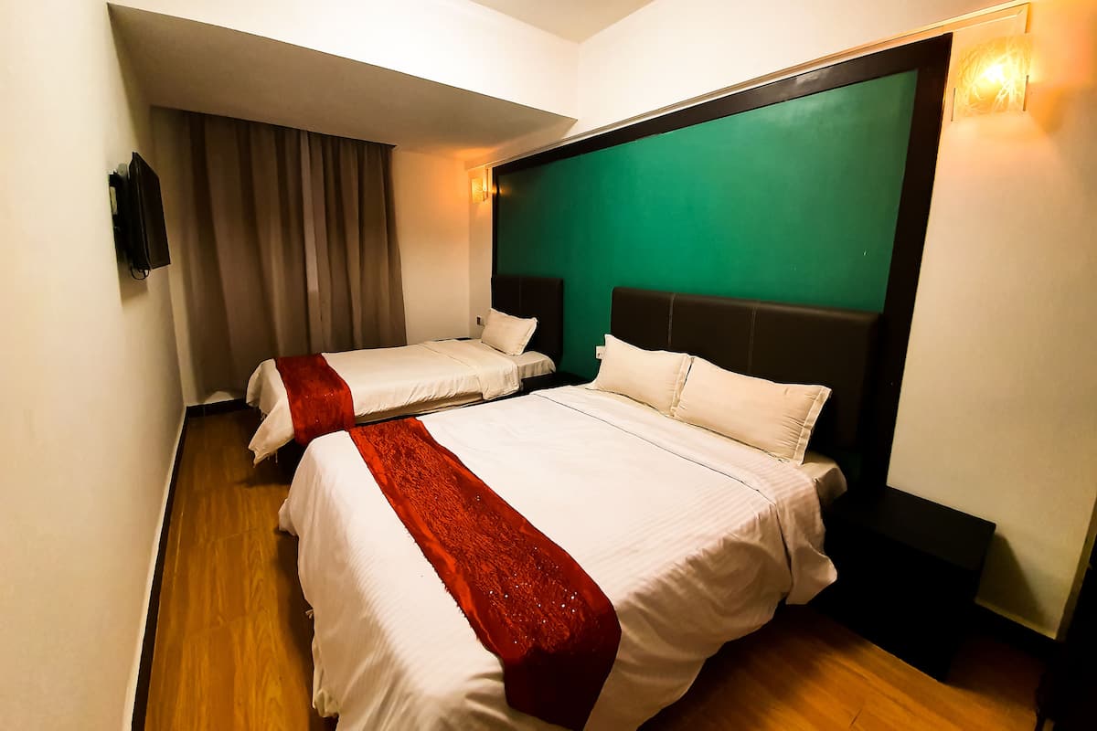 Une chambre d’hôtel avec deux lits, un mur d’accent de couleur verte et un plancher en bois.