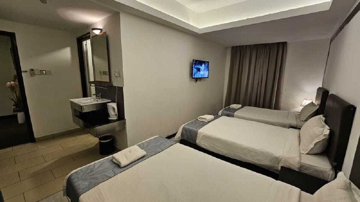 Una camera d'albergo con due letti, una TV, un bagno con specchio e una piccola scrivania.