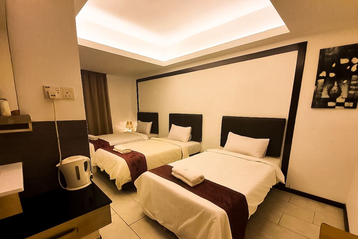 Une chambre d’hôtel avec deux lits, un bureau et un luminaire au plafond.