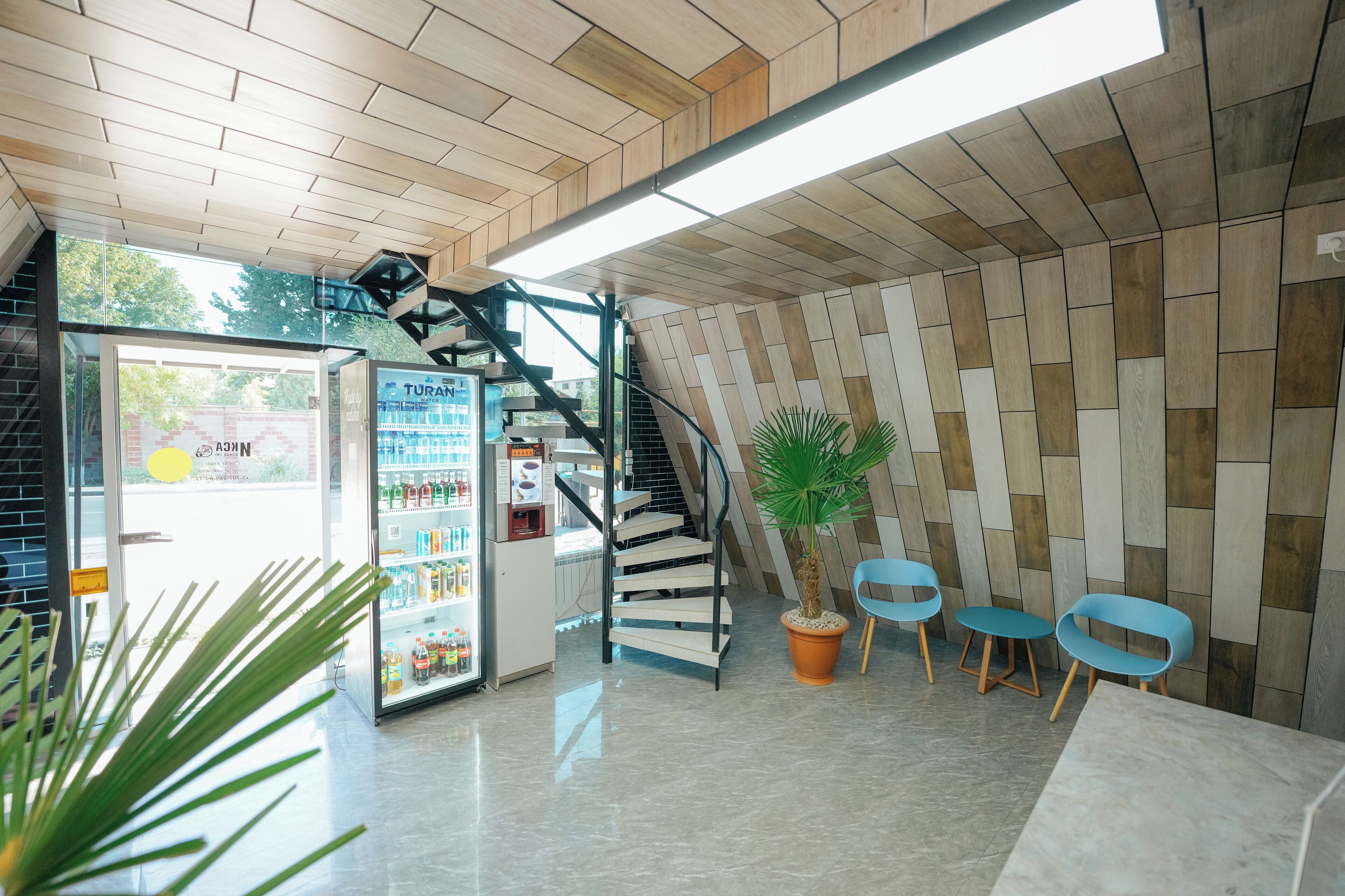 Un interior moderno con una escalera, una zona de estar y una máquina expendedora.