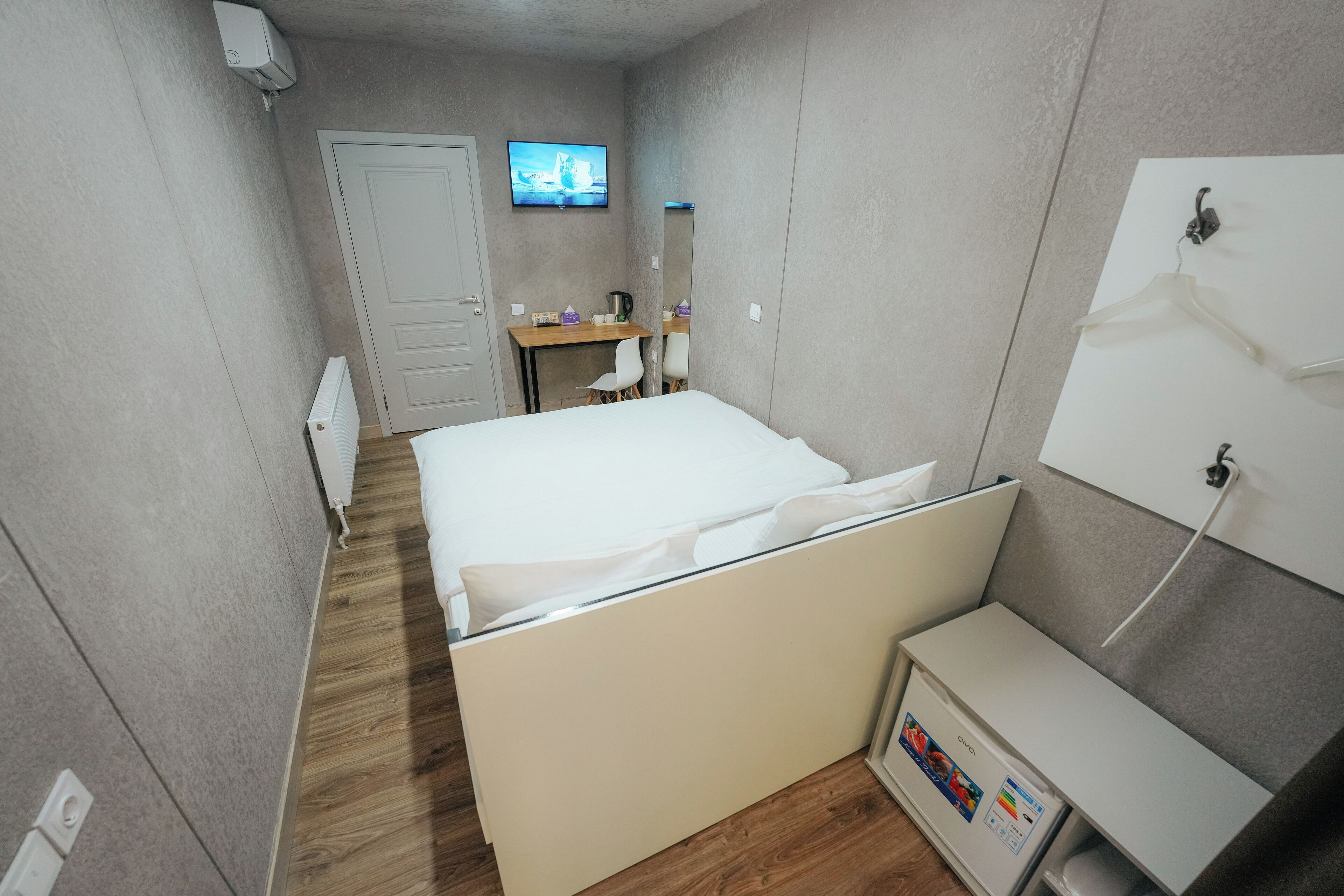 A hotel room with a bed, a desk, a chair, a TV, and a wardrobe.
