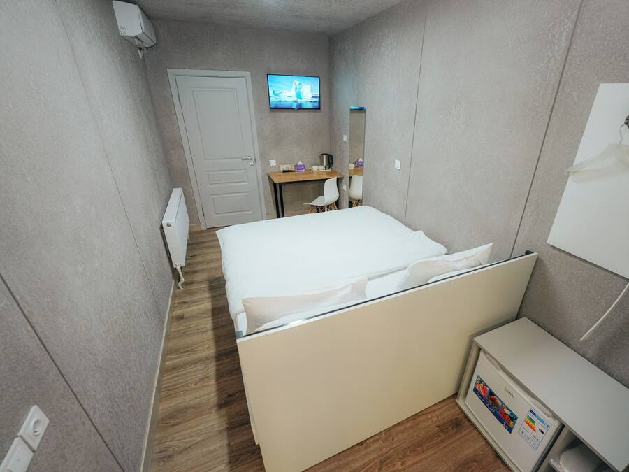 A hotel room with a bed, a desk, a chair, a TV, and a wardrobe.