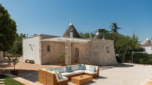 A stone building with a conical roof, a wooden bench, and a small tree. - Donna Vincenza in Selva di Fasano (Monopoli)