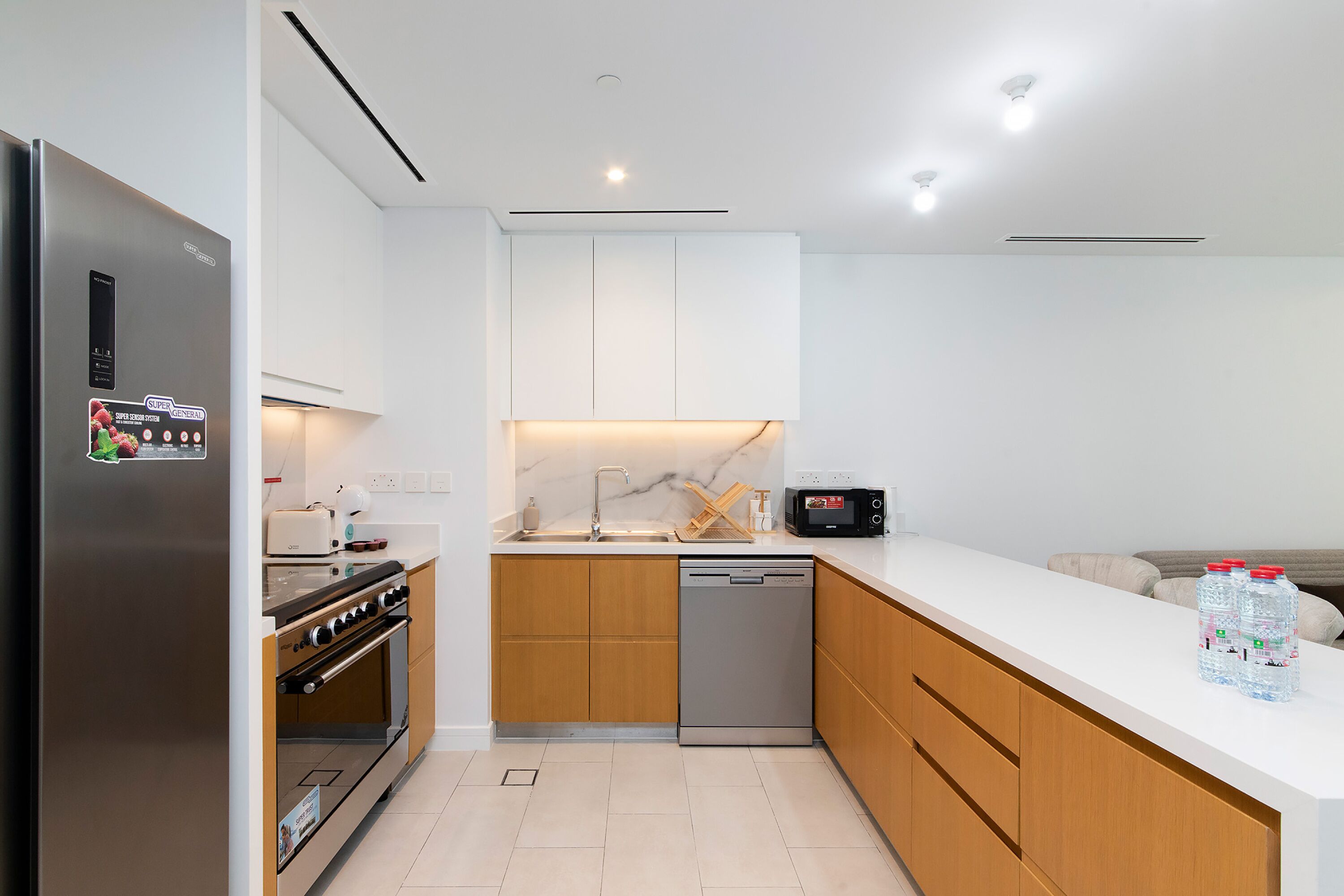 A modern kitchen with a stainless steel refrigerator, built-in oven, microwave, and dishwasher.