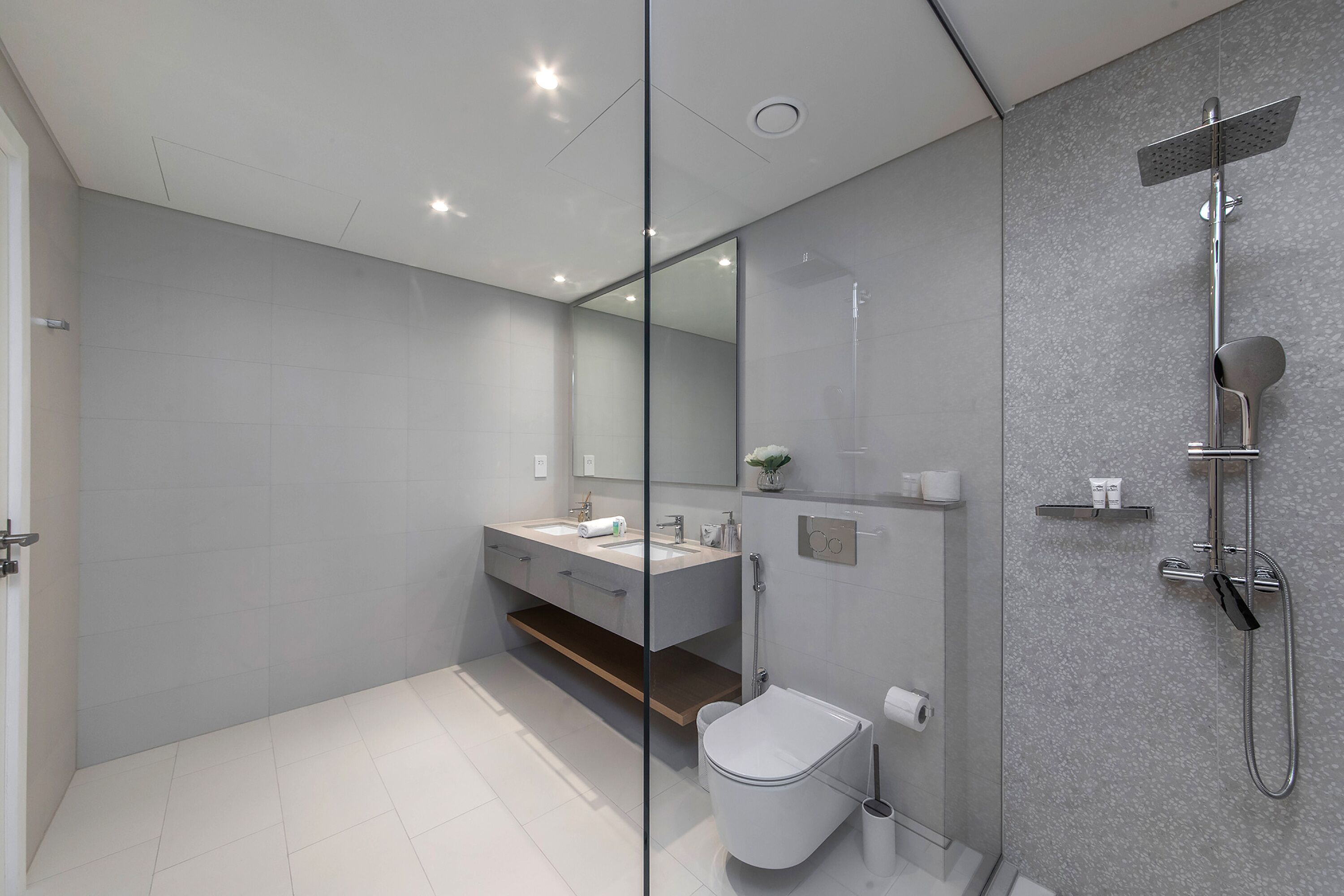 A modern bathroom with a glass partition, a shower, a toilet, and a vanity with a mirror.