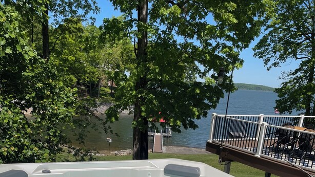 A hot tub with clear water, surrounded by trees and a view of a lake.