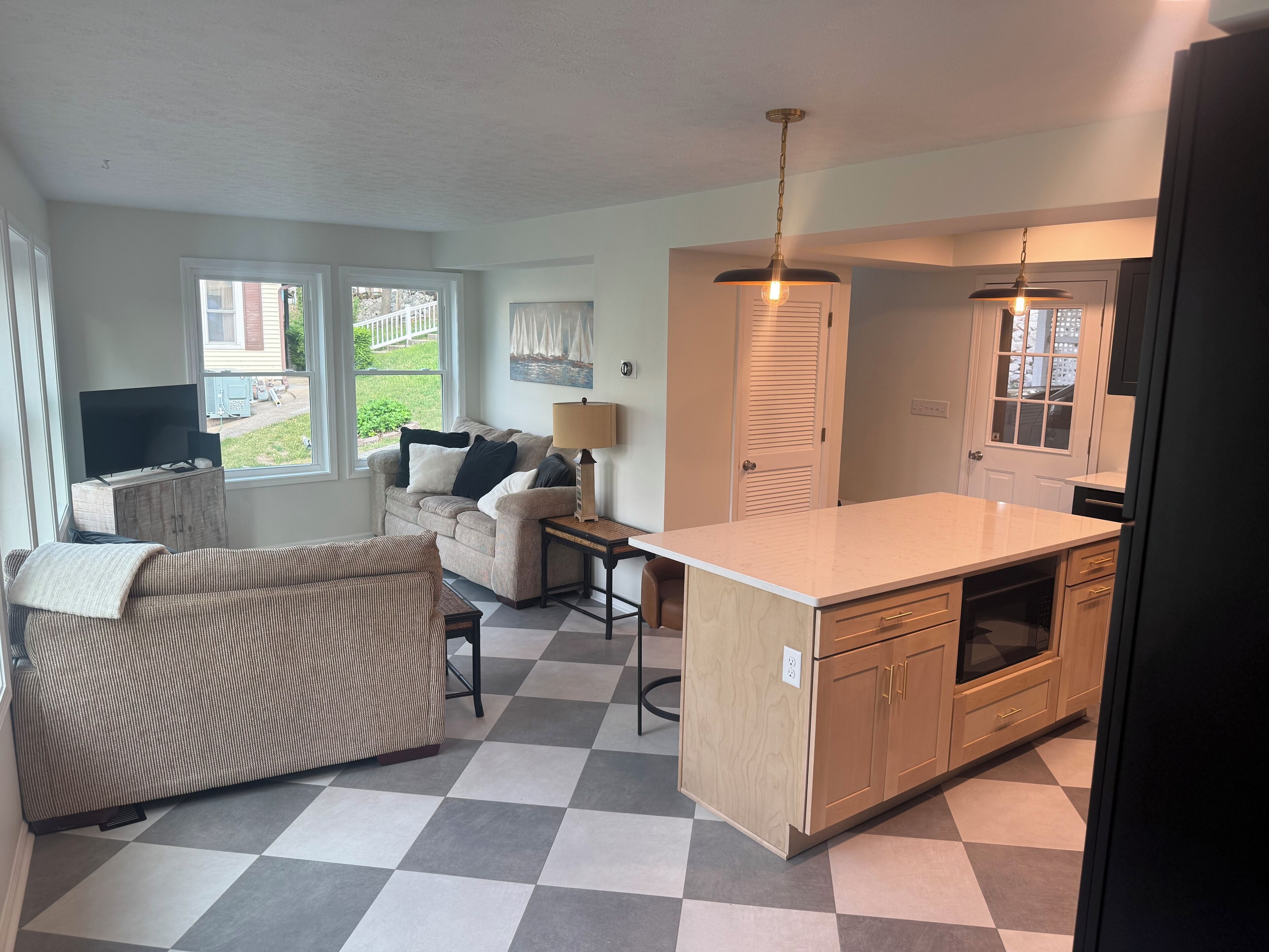 Un espacio habitable compacto con sofá, una mesa de comedor, una zona de cocina con armarios de madera y un televisor.