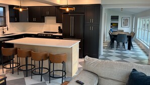 A modern kitchen with dark cabinets, a central island with stools, and pendant lighting.
