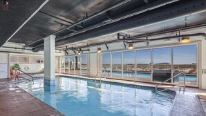 Una piscina interna con vista chiara sullo skyline cittadino attraverso ampie finestre.