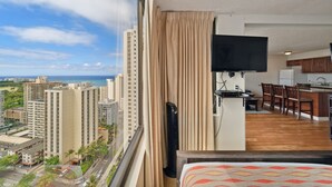 Ein Hotelzimmer mit großem Fenster, Flachbildfernseher, Küchenzeile und Essecke.