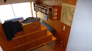 Un intérieur compact en bois, avec un lit superposé, une petite bibliothèque et une carte accrochée au mur.