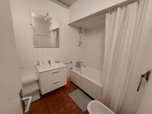 Uma casa de banho com uma pia branca, espelho e banheira.