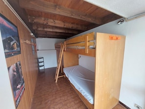 Quarto com beliches, paredes de madeira e chão revestido com azulejos.