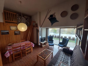 Uma sala de estar acolhedora com uma mesa de jantar de madeira, um sofá e uma televisão.