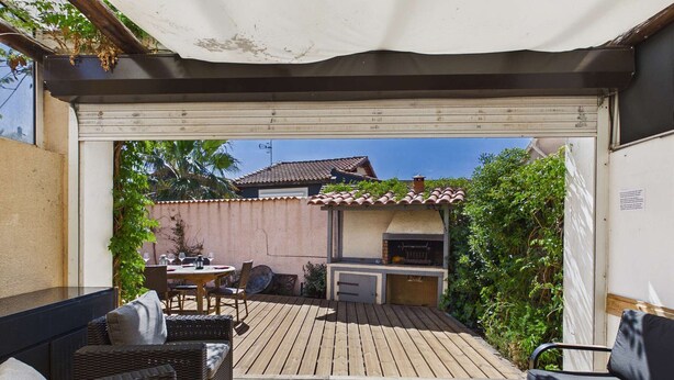 Une terrasse extérieure couverte, équipée d’une table à manger, de chaises et d’un barbecue.