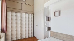 Une chambre à coucher comprenant un lit, une armoire, une porte et une étagère fixée au mur.