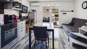 Une cuisine compacte dotée d’appareils électroménagers modernes, un coin repas avec une table et des chaises, et un espace de vie avec un canapé et une table basse.