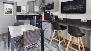 Une cuisine moderne avec une table à manger, des chaises, un téléviseur et une vue sur la ville.