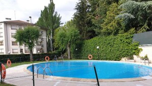 A swimming pool with a safety ladder, surrounded by a grassy area and trees. - Two-Bedroom Apartment with Pool, Balcony, and Garage in Tranquil Jaca (Jaca)