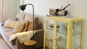 A living room with a sofa, a lamp, a glass cabinet with plates and glasses, and a decorative log. - Two-Bedroom Apartment with Pool, Balcony, and Garage in Tranquil Jaca (Jaca)