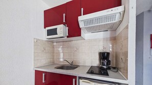 A compact kitchen with a microwave, coffee maker, and a dishwasher. - Stylish 2-Room Apartment with Balcony, Private Parking, Sleeps 4-6 (Marseillan-Plage)