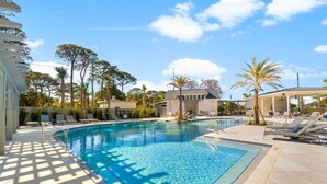 A swimming pool with sunlit tiled deck, lounge chairs, and palm trees. - Golf Cart ~ Oversized Deck ~ Water & Golf Views (Miramar Beach)
