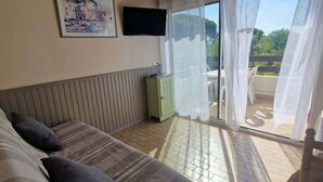 A bedroom with a bed, a television, a green cabinet, and a balcony with a view.
