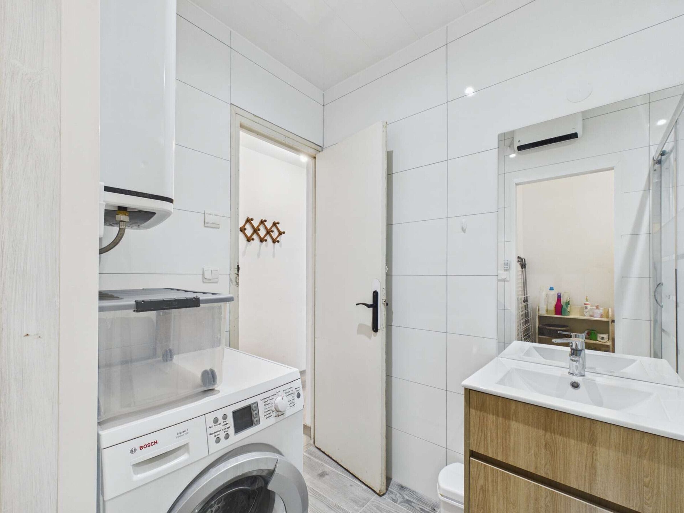 Un bagno moderno con una lavatrice Bosch, un lavandino con specchio e un water.