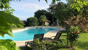 A rectangular swimming pool with a tiled edge, surrounded by a grassy area with a few chairs and a small rose bush. - Charming Countryside Retreat with Pool, Near Solesmes Abbey (Solesmes)