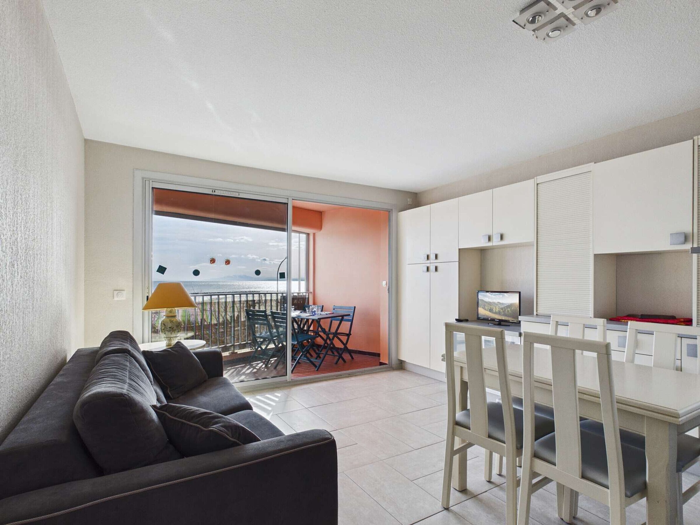 A modern apartment with a balcony, a sofa, a dining table, and a TV.