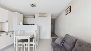A compact living space with a kitchenette, dining area, and a gray sofa. - Seaside Gem: Air-Conditioned 1-Bedroom Apartment with Ocean View Terrace at Grau d'Agde (Le Grau d'Agde)