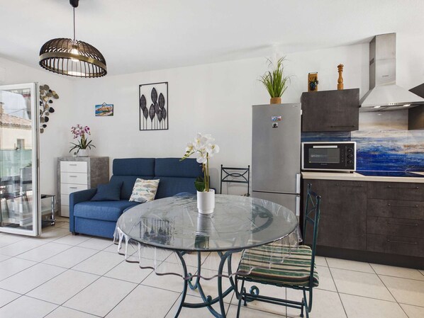 Eine moderne Küche mit Kühlschrank, Mikrowelle und einem Essbereich mit Glastisch und Stühlen.