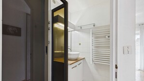 A modern bathroom with a glass shower enclosure, a white sink, and a towel rack. - Cozy 2-Room Apartment for 4 with Pool View, Terrace, and Private Parking (Marseillan-Plage)