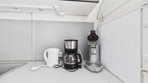 A kitchen with a coffee maker, a kettle, and a countertop. - Cozy 2-Room Apartment for 4 with Pool View, Terrace, and Private Parking (Marseillan-Plage)