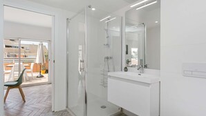 Een moderne badkamer met een douchecabine van glas, een witte wastafel en een grote spiegel.