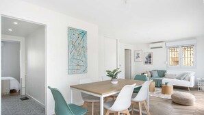Een moderne woonruimte met een eethoek, een bank en een raam met tralies.