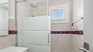 Un baño moderno con cabina de ducha de vidrio, bañera y ventana.