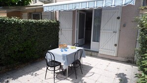 A patio with a table and chairs, a basket, and a tablecloth. - Modern 2-Bedroom Townhouse with Terrace, Private Parking & Pool Access in Marseillan (Marseillan-Plage)