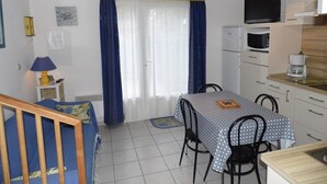 A compact living space with a dining area, kitchenette, and a small sofa. - Modern 2-Bedroom Townhouse with Terrace, Private Parking & Pool Access in Marseillan (Marseillan-Plage)