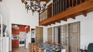 A dining area with a wooden table and chairs, a kitchen in the background, and a staircase leading to an upper level. - Spacious house 70m from the sea, Le Grau d'Agde (Le Grau d'Agde)