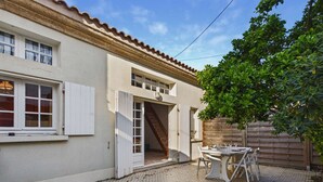A house with a tiled patio, a wooden fence, and a tree. - Spacious house 70m from the sea, Le Grau d'Agde (Le Grau d'Agde)