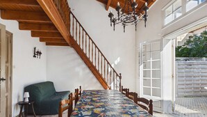 A dining room with a long table, wooden staircase, chandelier, and a view through an open door. - Spacious house 70m from the sea, Le Grau d'Agde (Le Grau d'Agde)