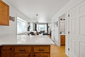 Una cocina moderna con una isla grande, armarios de madera y vistas al comedor.