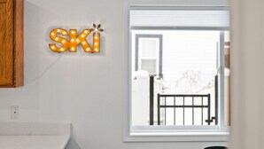 Una habitación con ventana, un aplique de pared que dice 'SKI' y un armario de madera.