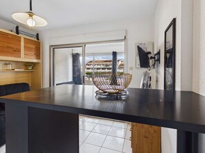 Uma cozinha moderna com bancada preta, prateleiras de madeira e uma grande janela com vista para edifícios.