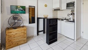 A modern kitchen with white cabinets, a microwave, a sink, and a fan. - Cozy Studio Apartment with Pool Access near Beach in Marseillan, Sleeps 4 (Marseillan-Plage)